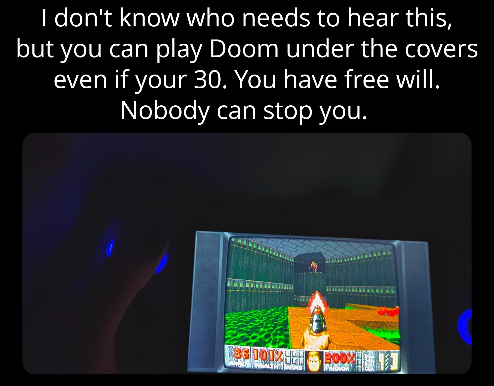 Text reads: "I don't know who needs to hear this, but you can play Doom under the covers even if you're 30. You have free will. Nobody can stop you." Below is a picture of Doom being played on a handheld under the covers. 