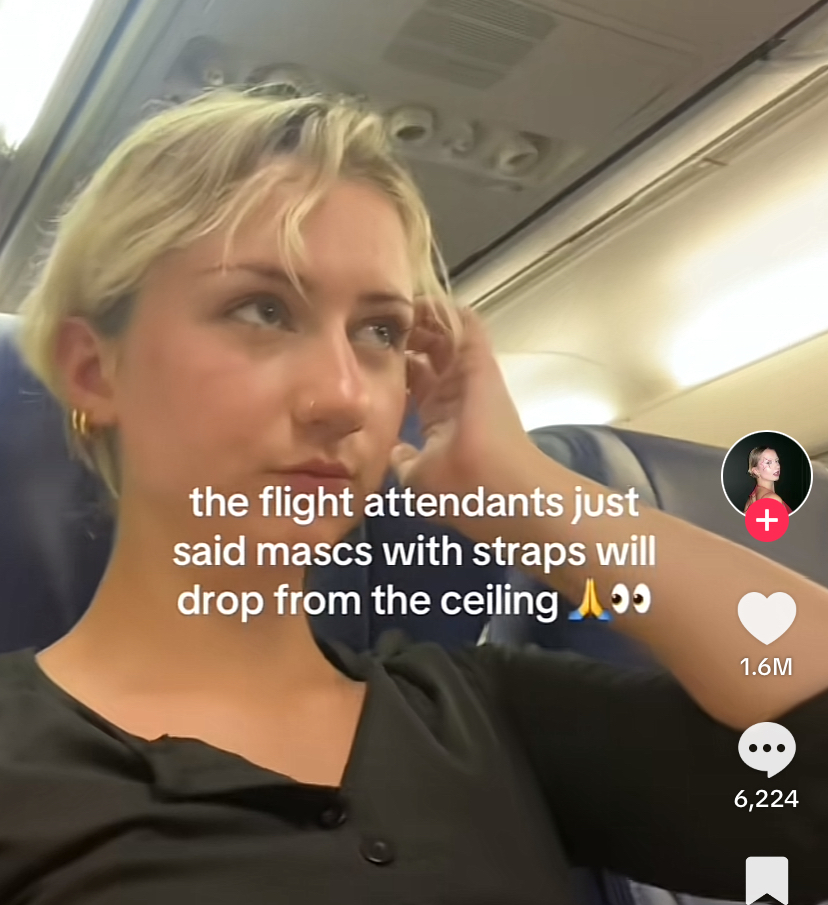 Person sitting in an airplane seat playing flirtatiously with their hair. The caption says that the flight attendant just said mascs (with a c) with straps will drop from the ceiling.